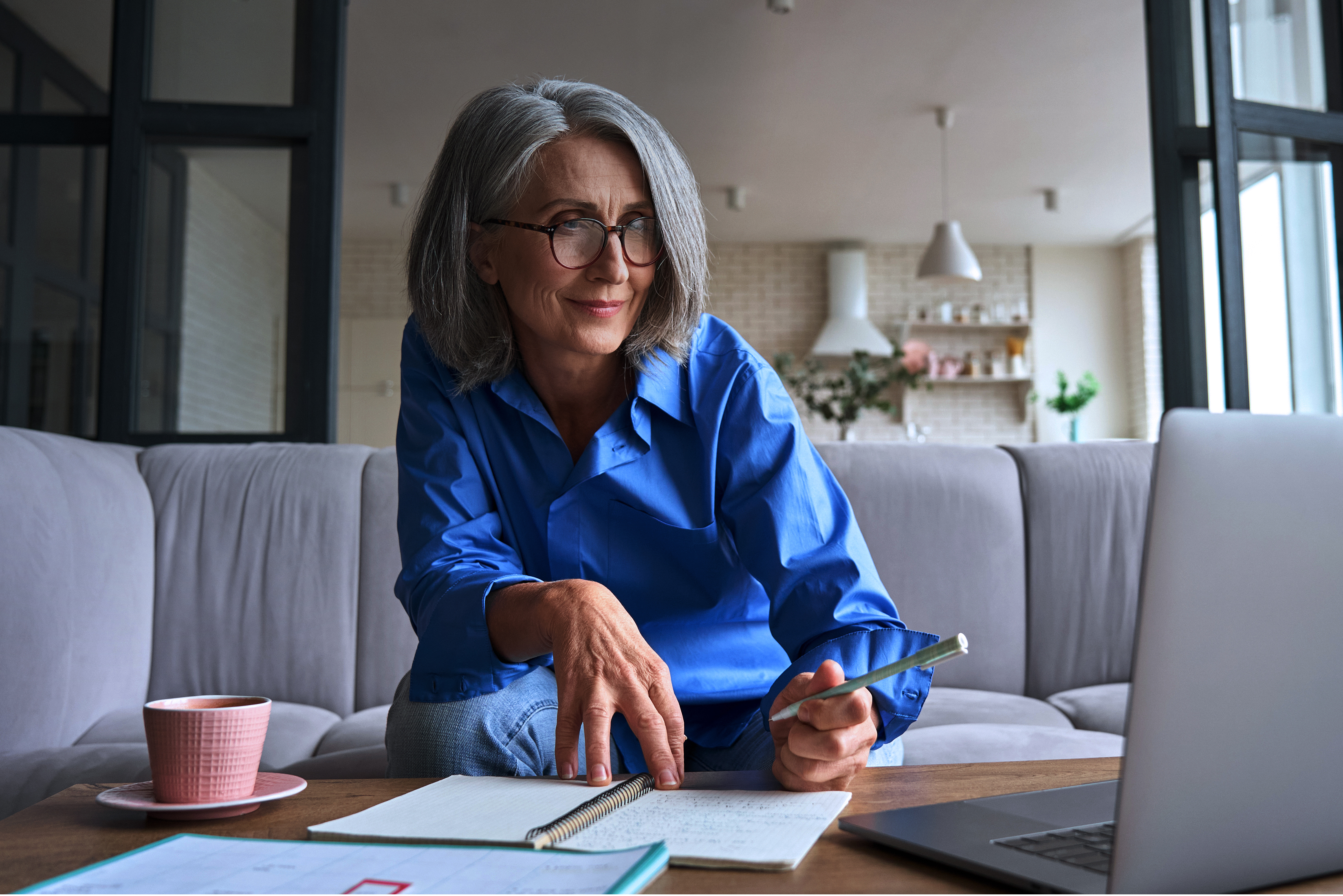 Middle-aged woman sitting on couch, working on laptop